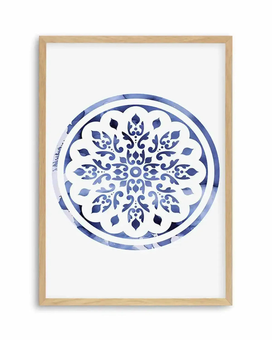 Watercolour art print featuring a circular mandala design with intricate floral and scrollwork patterns in varying shades of blue, from deep navy to pale sky blue, on a white background, printed on fine art paper and displayed in a natural oak frame with white border.