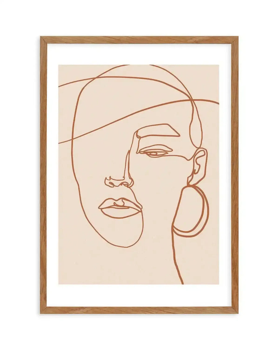 Line art print featuring a minimalist abstract portrait of a woman's face, drawn with continuous terracotta-coloured lines on a warm cream background, displayed in a natural oak frame with white border. The composition shows one eye, a nose, and lips, with an abstract ear and large hoop earring on the right side, and flowing lines suggesting hair or contours.