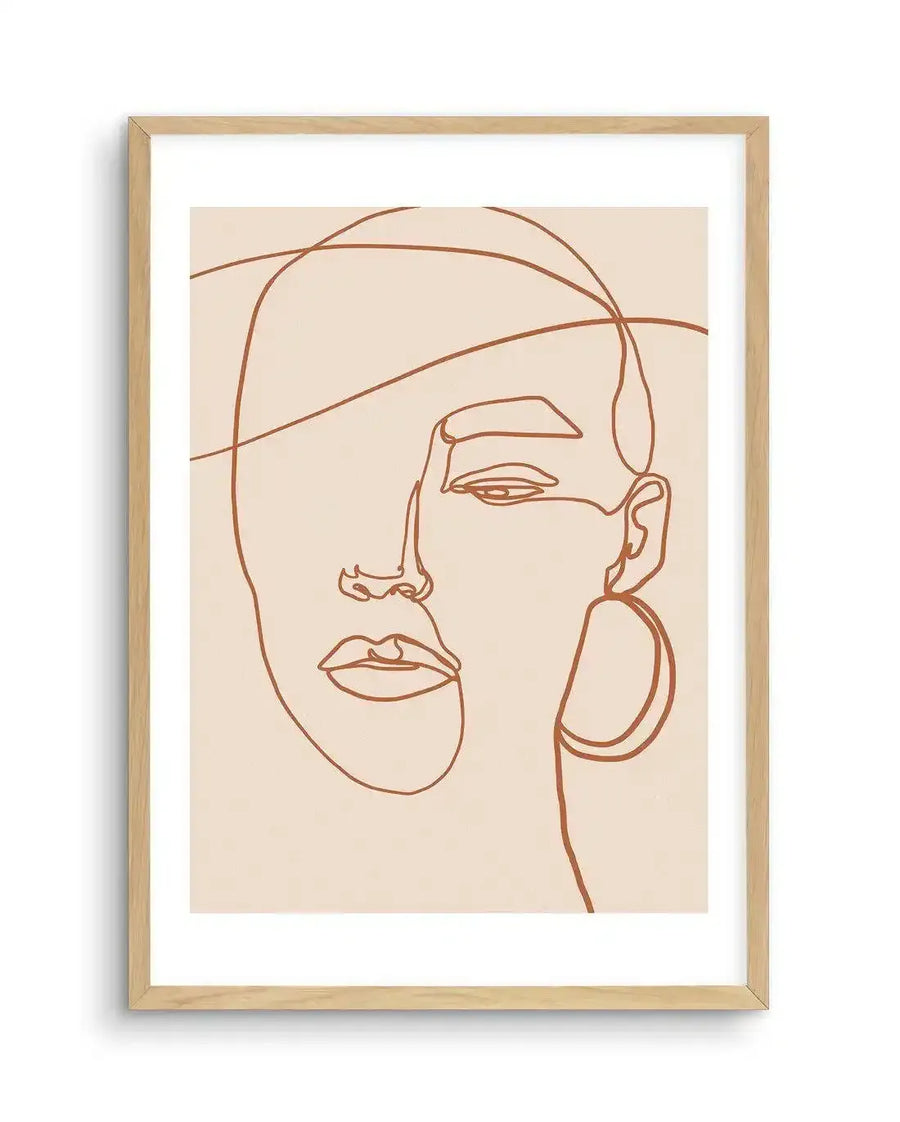 Line art print featuring a single continuous line forming the abstract contours of a woman's face in terracotta brown on a pale cream background, displayed in a natural oak frame with white border.