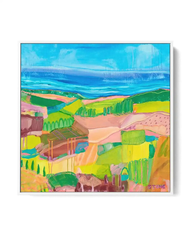 Abstract canvas print featuring a vibrant landscape with a bright blue sky and ocean horizon, with rolling hills and fields in shades of lime green, yellow, and peach, dotted with darker green trees and hints of brown structures. The artwork has a painterly, expressive quality with visible brushstrokes and a signature "STONE" in the bottom right corner, displayed in a white frame.