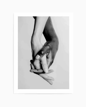 Black and white photograph of two hands, one light-skinned and one dark-skinned, clasped together in a gentle hold, printed on fine art paper with a matte finish. The composition emphasizes unity and connection.