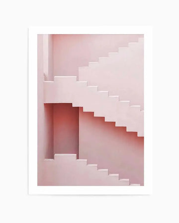 Product shot art print featuring a minimalist architectural photograph of a pink staircase with clean lines and geometric shapes. The composition shows two flights of stairs, one ascending from the lower left and another descending from the upper right, meeting at a landing with a recessed alcove. The walls and stairs are a uniform soft blush pink, creating a serene and modern aesthetic.
