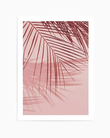 Photography art print featuring the silhouette of palm fronds in a deep rose pink against a soft blush pink background, creating a minimalist tropical aesthetic. The composition highlights the delicate lines of the fronds and their shadows cast on the background.
