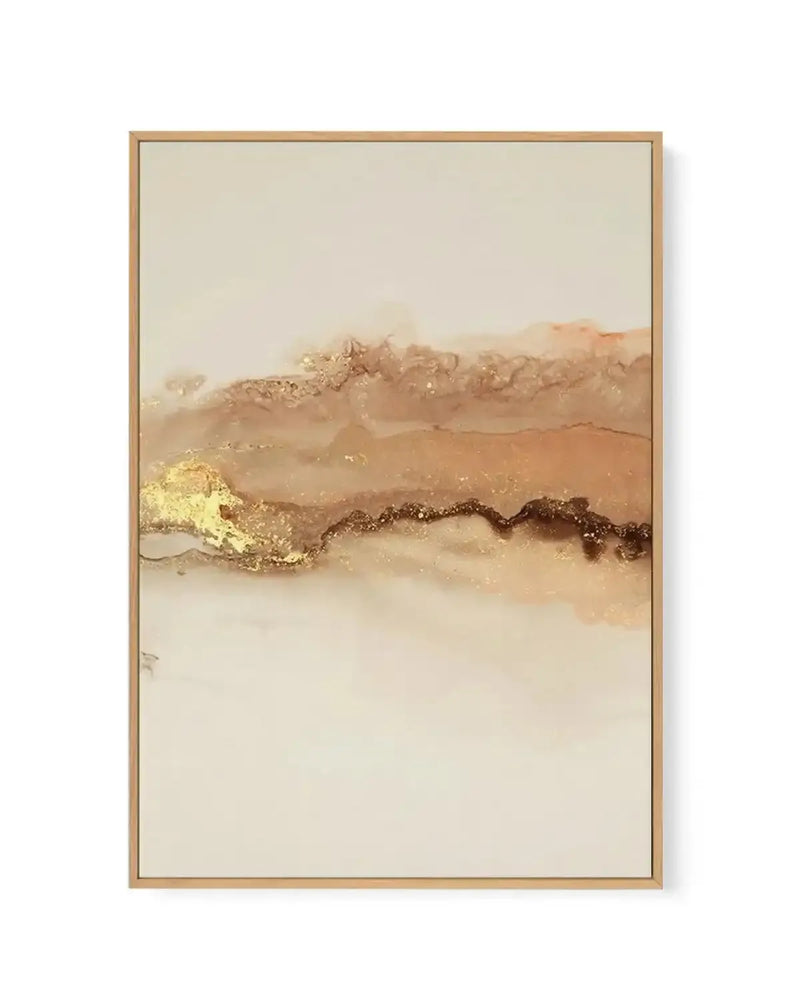 Framed canvas art print featuring an abstract landscape with soft, muted tones of cream, beige, tan, and warm brown. Horizontal brushstrokes and watercolor-like washes create layered terrain suggesting rolling hills or desert dunes. A decorative band of gold and dark brown metallic accents runs horizontally through the center, adding texture and shimmer. The composition is minimalist and peaceful with a hazy, atmospheric quality. Natural wood frame in light tan shown with white border.