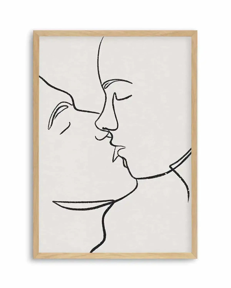 Line art print featuring two faces in profile, nose to nose, as if about to kiss, with closed eyes and soft, flowing lines in black on a white background, displayed in a natural oak frame with white border.