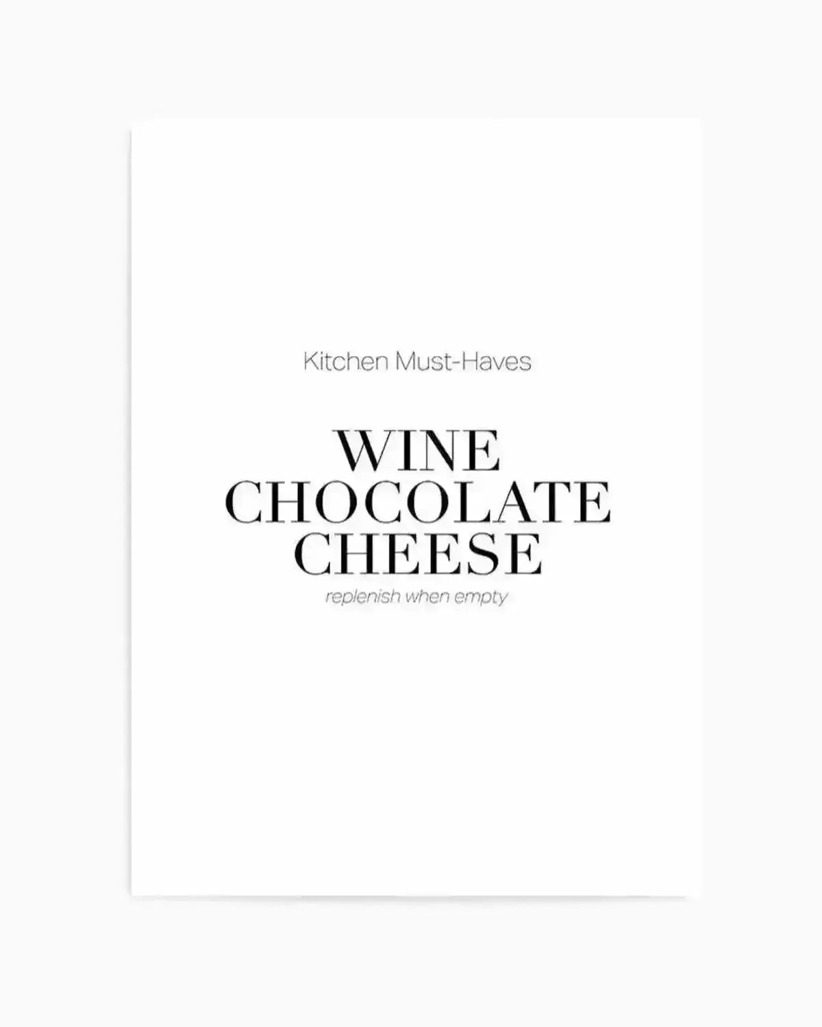 Art print with minimalist design on white background featuring "Kitchen Must-Haves" in small gray sans-serif text at top, followed by "WINE CHOCOLATE CHEESE" in large black serif typography centered on page, with "replenish when empty" in small gray italicized text below. Clean, modern aesthetic with generous white space. Unframed print shown as product shot.