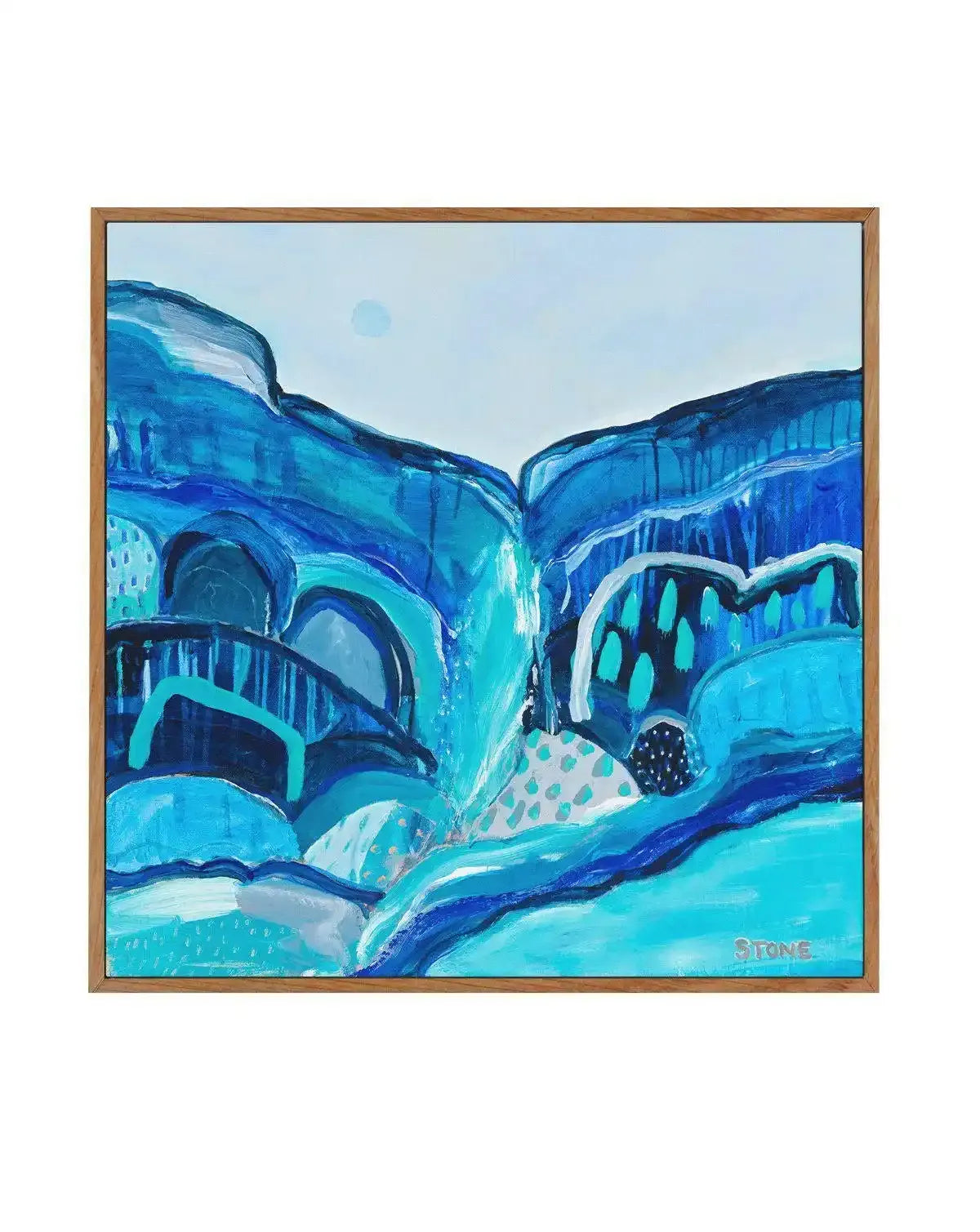 Abstract canvas print featuring a vibrant landscape of layered blue and turquoise shapes, suggestive of a lagoon or river flowing through a valley, with a light blue sky and a subtle pale blue circle. The artwork has visible brushstroke texture and is displayed in a natural oak frame.