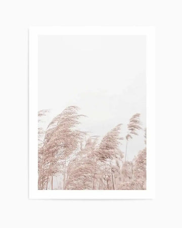Photography art print featuring a field of pampas grass in soft, muted blush pink and beige tones, swaying gently in the wind against a bright, hazy white sky. The composition captures the delicate, feathery texture of the grass with a light and airy mood.