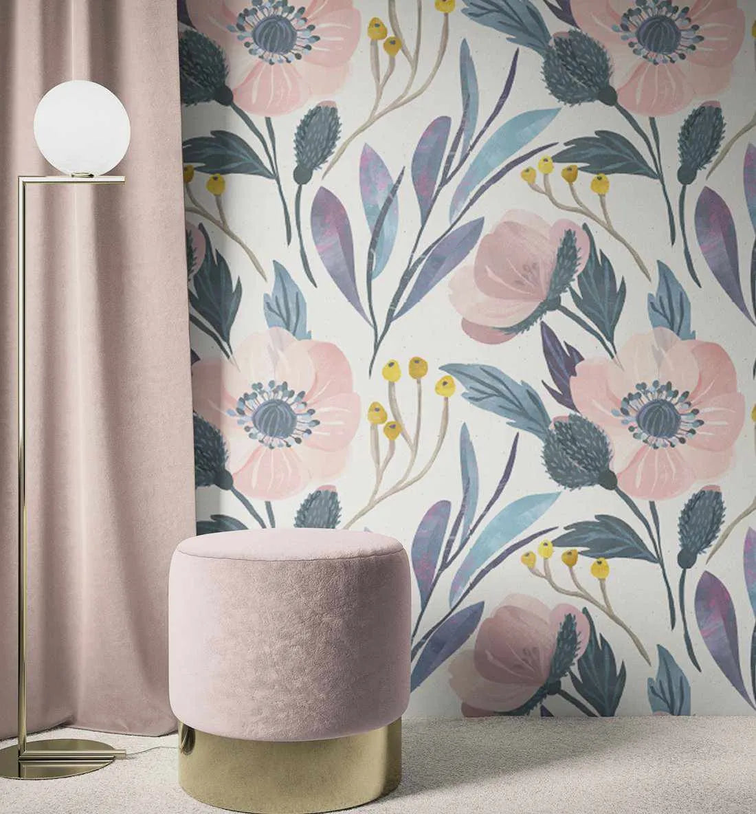 Lifestyle shot of a room with Laras Garden wallpaper featuring a repeating pattern of hand-painted pink poppy-like flowers with blue-grey centers, blue-grey leaves, and yellow berries on a white background. The wallpaper has a loose, organic watercolor quality with visible brushstroke texture. A dusty rose velvet curtain hangs on the left, and a matching dusty rose velvet ottoman with a gold base sits on a light-colored carpet. A modern floor lamp with a white spherical light stands next to the curtain.