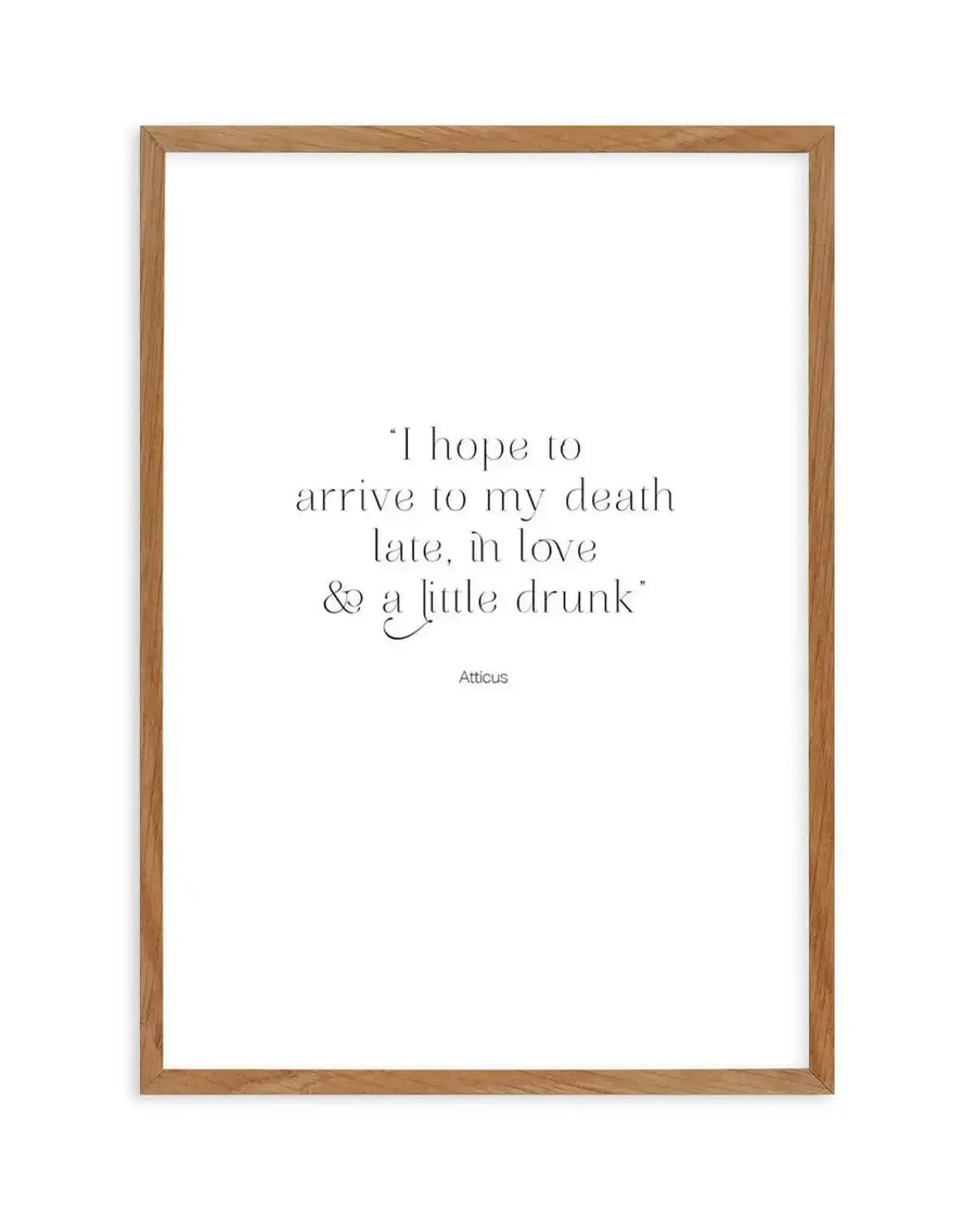 Art print featuring the quote "I hope to arrive to my death late, in love & a little drunk" in black serif font with a decorative ampersand, printed on fine art paper and displayed in a natural oak frame with white border.