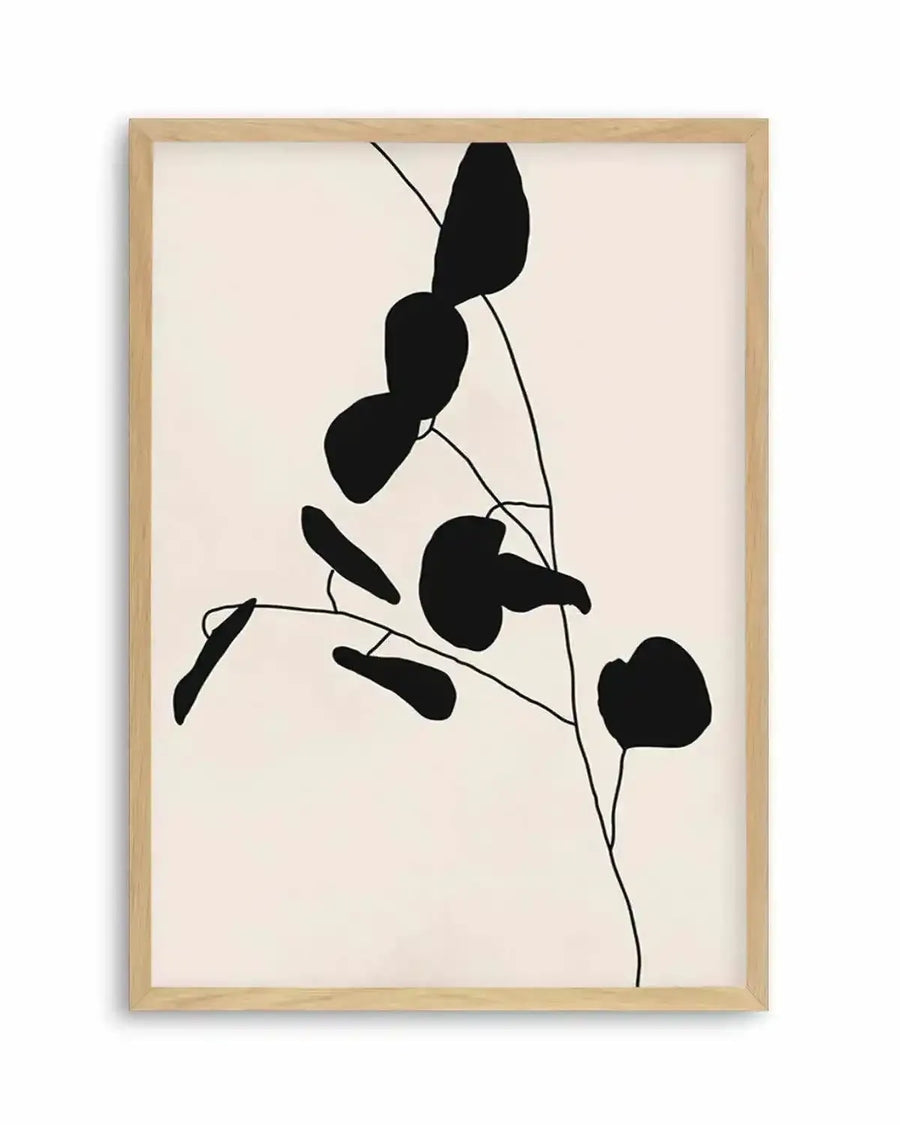 Art print featuring minimalist black silhouettes of eucalyptus leaves and branches on a warm cream background, printed on fine art paper and displayed in a natural oak frame with white border.