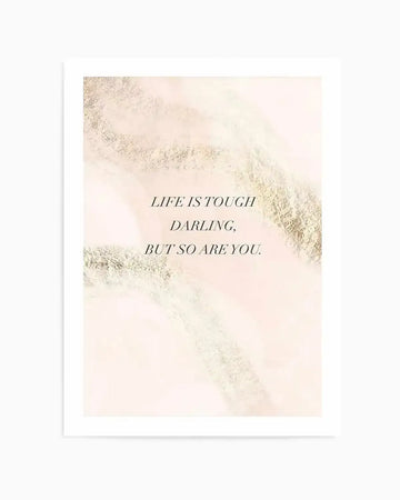 Art print featuring the quote "LIFE IS TOUGH DARLING, BUT SO ARE YOU." in black serif font, set against a soft blush pink background with abstract, shimmering gold and cream textured brushstrokes. The print is displayed with a white border.