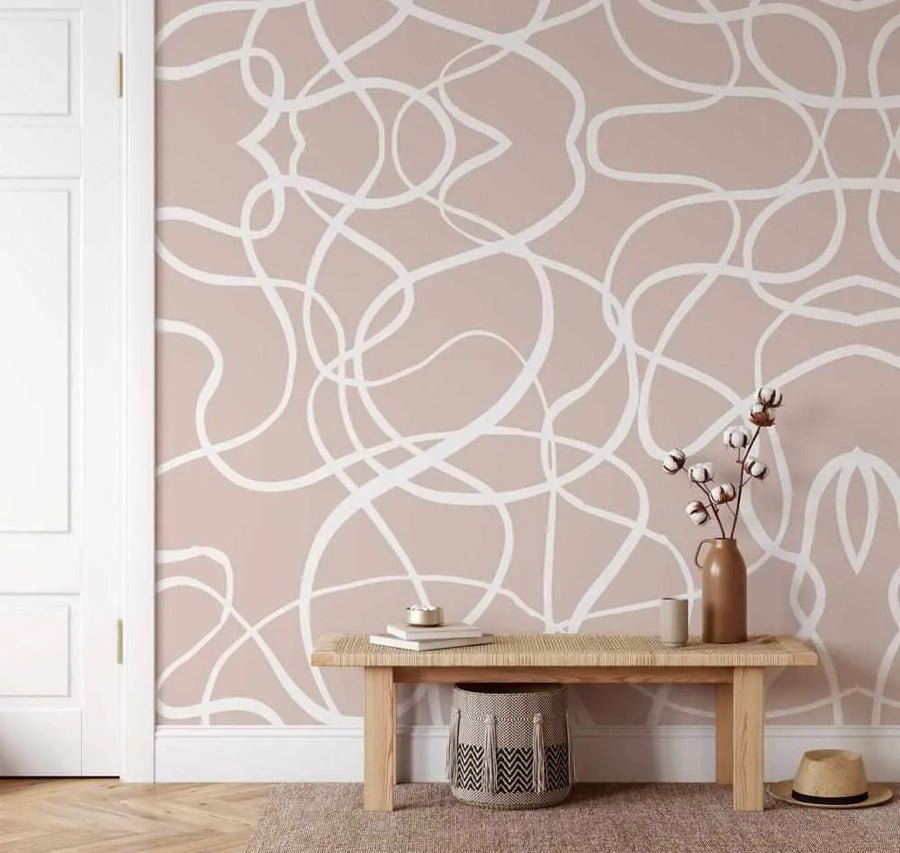 Entryway:
Peel and stick wallpaper featuring a repeating pattern of hand-drawn, free-flowing white lines that loop and intertwine on a soft, muted nude pink background, creating an abstract, organic design. The wallpaper is displayed in an entryway with a light wood bench, a woven basket, and a vase with cotton branches.