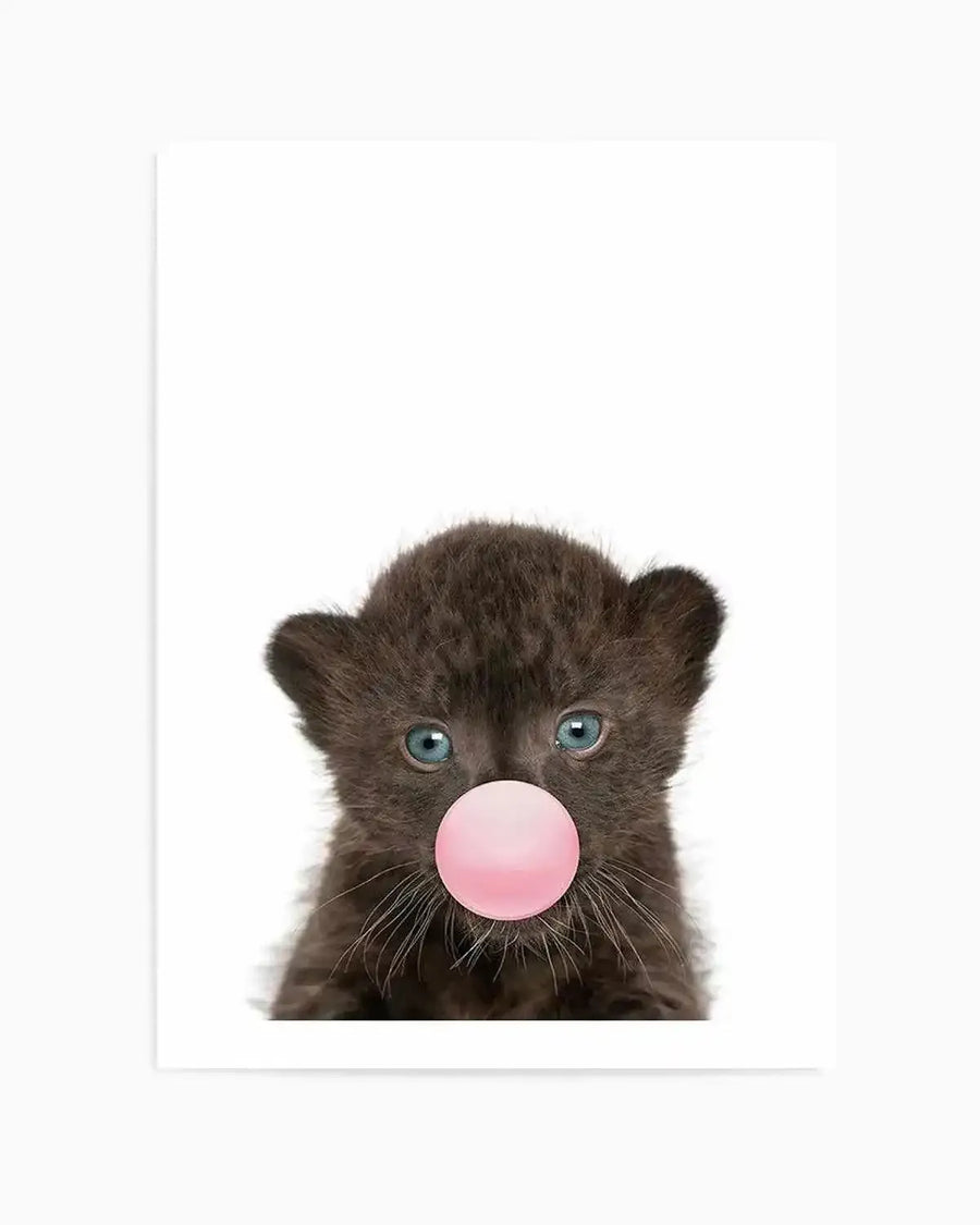 "Photography art print featuring a close-up of a tiny black leopard cub with bright blue eyes, blowing a perfectly round, light pink bubble of gum. The cub's dark, soft fur and delicate whiskers are visible against a stark white background, creating a playful and endearing composition."