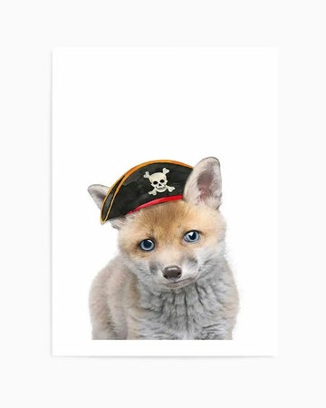 Photography art print featuring a baby fox wearing a black pirate hat with a white skull and crossbones emblem, set against a plain white background. The fox has light brown and grey fur, bright blue eyes, and a small dark nose, looking directly at the viewer with a curious expression.
