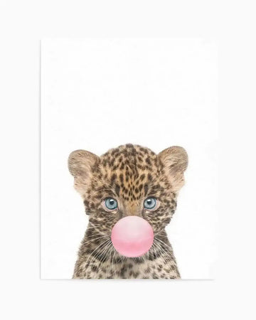 Illustration of a young leopard cub with spotted tan and brown fur and bright blue eyes, blowing a large bubble gum bubble in soft pink. The cub's face fills most of a white background in a centered composition. The artwork has a soft, detailed style with fine fur texture rendered in natural earth tones. The print is displayed on a white background with a subtle white border.