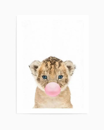 Art print featuring a baby lion cub with bright blue eyes, looking directly forward, blowing a large pink bubble gum bubble. The cub has soft, light brown fur with darker brown spots and stripes, set against a clean white background.