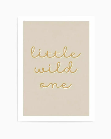 Art print featuring the phrase "little wild one" in a delicate, flowing script in a warm golden-yellow hue, set against a soft, muted beige background, with a white border.
