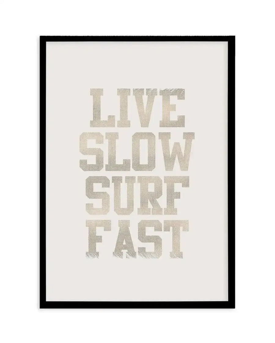 Art print featuring the words "LIVE SLOW SURF FAST" in a distressed, textured, light grey font on a plain white background, displayed in a black frame with a white border.