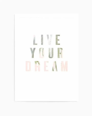 Art print featuring the motivational text "LIVE YOUR DREAM" arranged in three centered lines on a white background. The letters have a translucent, layered quality with soft sage green, pale pink, and cream tones, overlaid with botanical imagery including palm fronds and delicate leaf textures. The overall aesthetic is minimalist and calming with a soft, watercolor-like quality. The print is mounted on white with a simple white border frame visible on the left edge.
