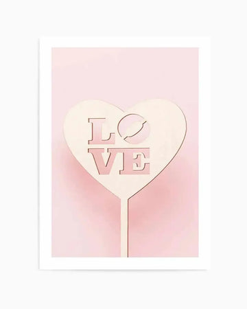 Art print featuring a pale pink heart-shaped sign with the word "LOVE" cut out in a bold, blocky font, displayed against a soft blush pink background. The "O" in "LOVE" is represented by a diagonal slash through a circle. The sign has a smooth, matte finish.