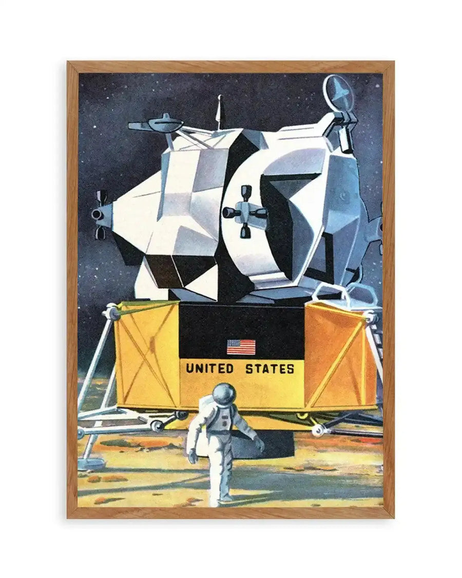 "Retro-style art print depicting an astronaut on the moon next to a lunar lander, displayed in a natural oak frame with white border. The illustration features a white and grey lunar module with a black base and yellow panels, an American flag, and "UNITED STATES" text, set against a dark blue starry sky and a muted orange moon surface."