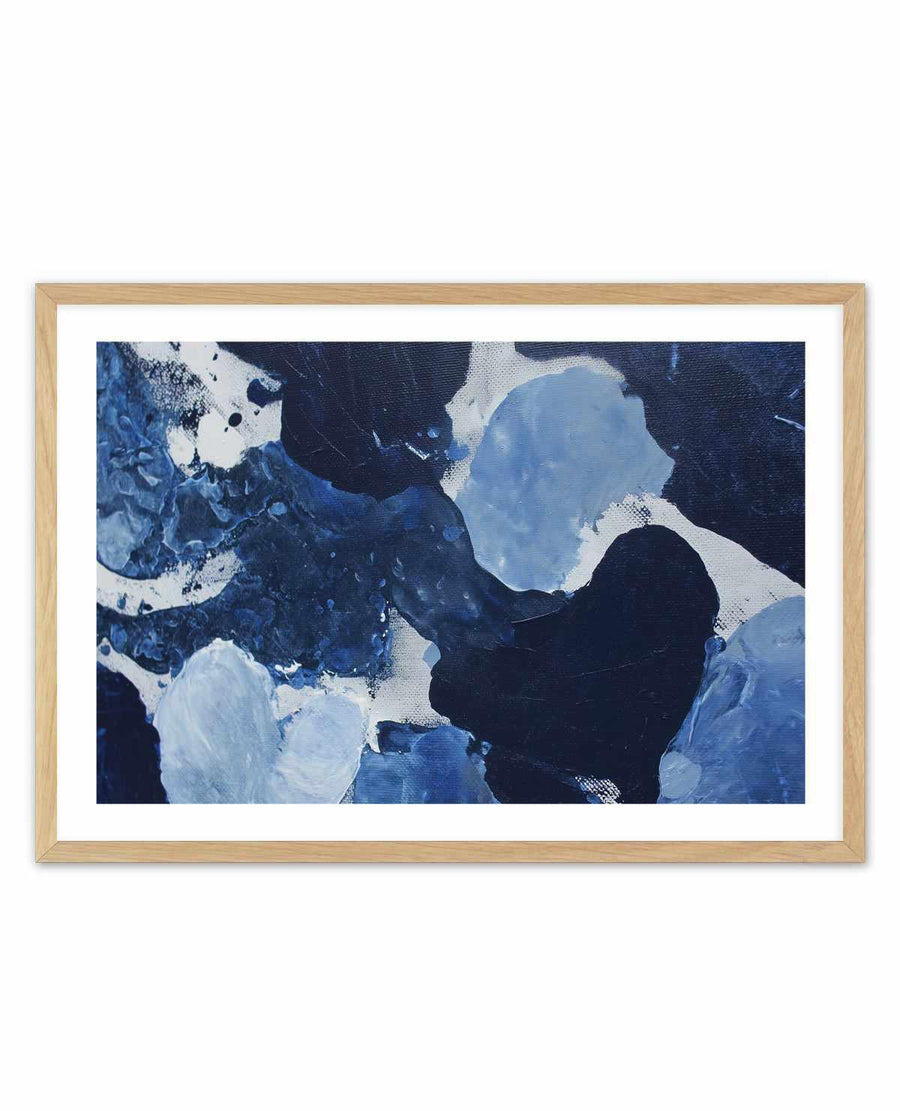 Framed art print titled Midnight Current II featuring an abstract composition in shades of navy, deep blue, light blue, and white. The painting depicts organic, flowing shapes and gestural brushstrokes creating a dynamic, fluid aesthetic reminiscent of water currents or natural phenomena. The artwork is displayed in a natural wood frame with a white border, mounted on a white background.