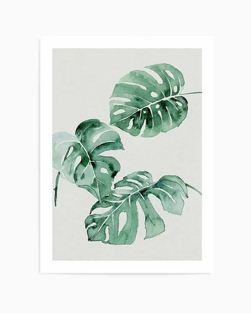 Watercolour art print featuring three Monstera deliciosa leaves arranged vertically on a cream background. The leaves are rendered in varying shades of green with lighter green and white highlights, displaying the characteristic split and hole patterns of the plant. The paint has soft, translucent qualities with organic brushwork creating subtle colour variations and depth. The artwork is mounted in a white border frame.