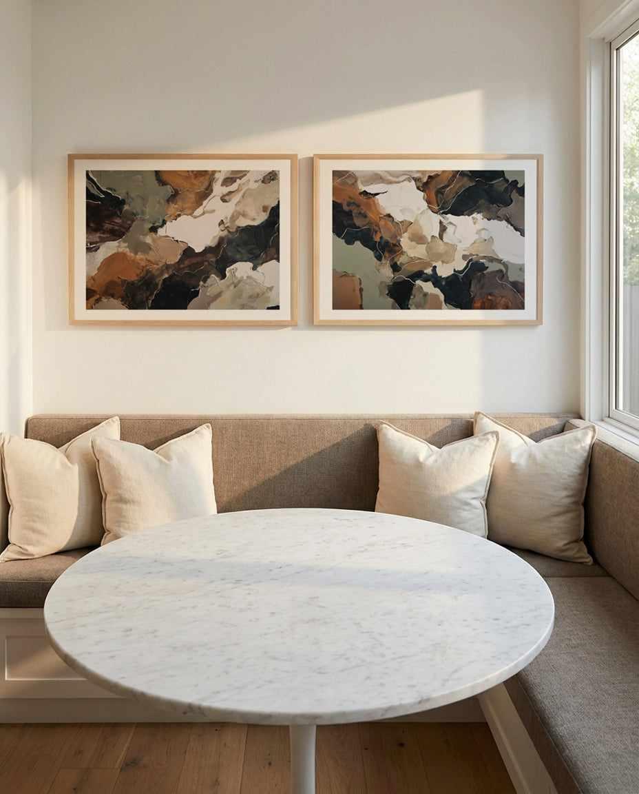 Abstract art print titled Ochre Ridge I displayed in natural wood frame with white border, hung on cream wall above beige upholstered banquette. Artwork features organic, flowing composition in earthy tones including burnt orange, chocolate brown, charcoal black, cream, and sage green, with soft watercolor-like blending creating a landscape-inspired abstract aesthetic. Framed print shown in styled living room setting with marble-topped round table and cream pillows on seating.