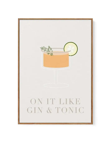 Framed canvas art print with a warm beige background featuring an illustration of a cocktail in a coupe glass filled with golden-orange liquid, garnished with a lime wheel and fresh herb sprigs. Below the drink illustration, text reads "ON IT LIKE GIN & TONIC" in muted sage green lettering. The canvas is set in a natural wood-toned frame with a white border.