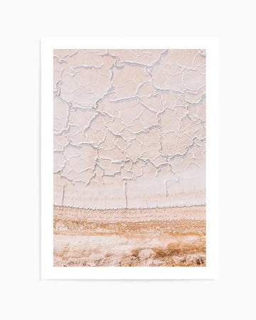 Art Print (abstract):
Abstract art print featuring an aerial view of cracked, dry earth in pale blush pink and cream, with a horizontal band of rich terracotta and sandy brown at the bottom. The composition suggests a parched landscape or salt flats, with intricate, organic crack patterns.