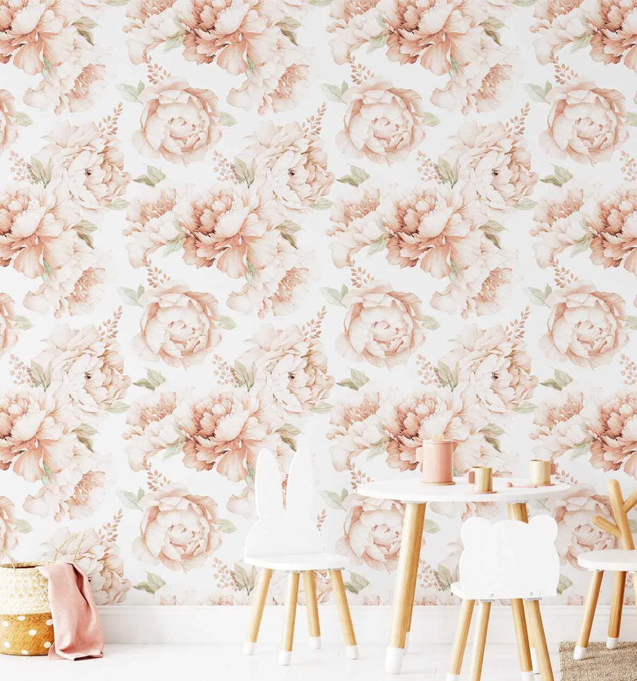 Kids Room:
"Peel and stick wallpaper featuring a repeating pattern of large-scale peony roses in soft terracotta, blush pink, and cream with delicate sage green leaves on a white background, displayed in a child's room. The wallpaper covers a wall behind a small white table with two bunny-ear chairs and a bear-ear chair, and a woven basket with a pink cloth on the left."