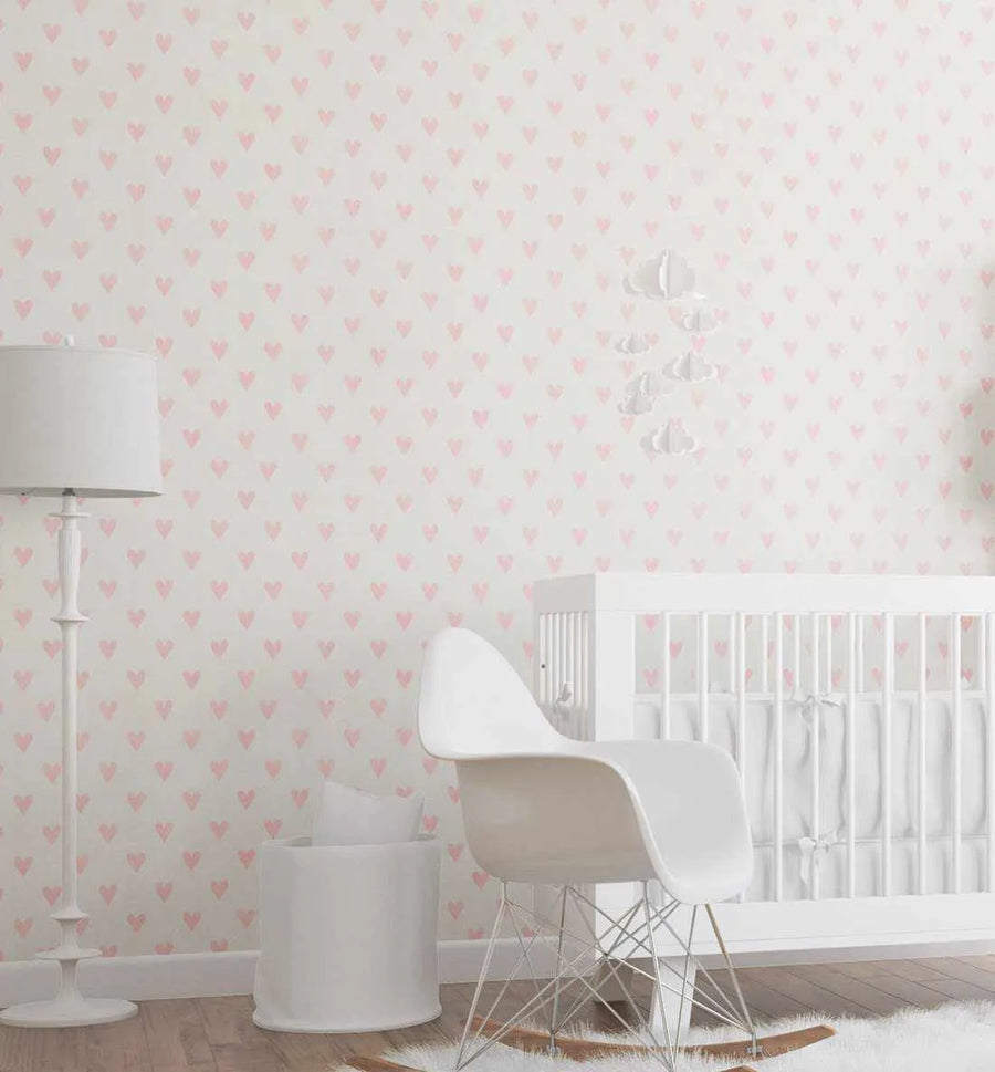 Nursery:
"Pink Hearts Wallpaper displayed in a minimalist nursery. The wallpaper features a repeating pattern of small, hand-painted hearts in a soft blush pink on a clean white background. The room includes a white crib with white bedding, a white rocking chair with a metal base, a tall white floor lamp, and a white storage bin, all set on a light wood floor with a white fluffy rug."