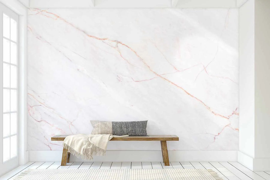 Hallway:
Peel and stick wallpaper featuring a large-scale, organic pattern of delicate pink and rose gold veins on a soft white marble background, displayed on a wall in a minimalist hallway. The wallpaper has a smooth, matte finish, and the room includes a light wood bench with a cream throw and two textured cushions, a white rug, and white wooden floorboards.