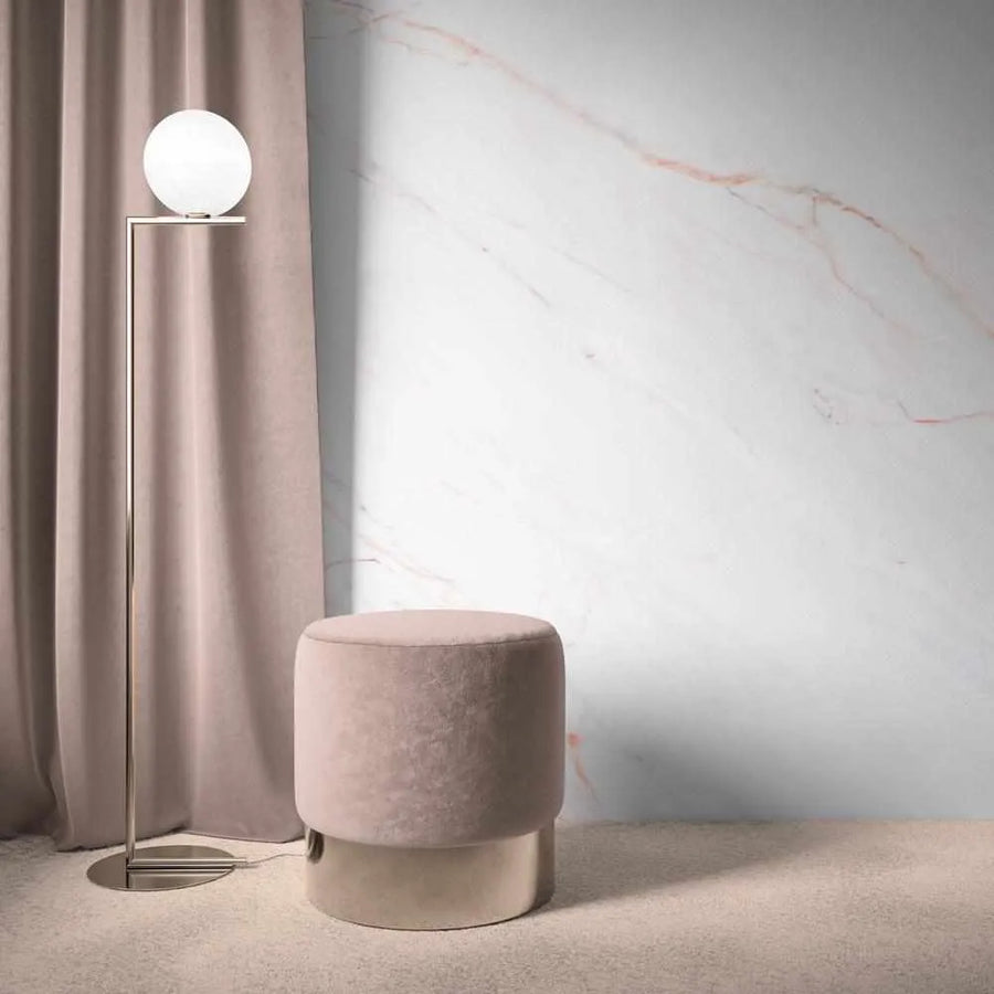 Room:
"A minimalist room featuring a floor lamp with a spherical white light, a round dusty rose velvet ottoman with a metallic base, and a wall covered in peel and stick wallpaper. The wallpaper features a white marble design with delicate, irregular veins in soft pink and light grey, creating a luxurious and serene atmosphere. The floor is covered in a light-coloured, textured carpet."