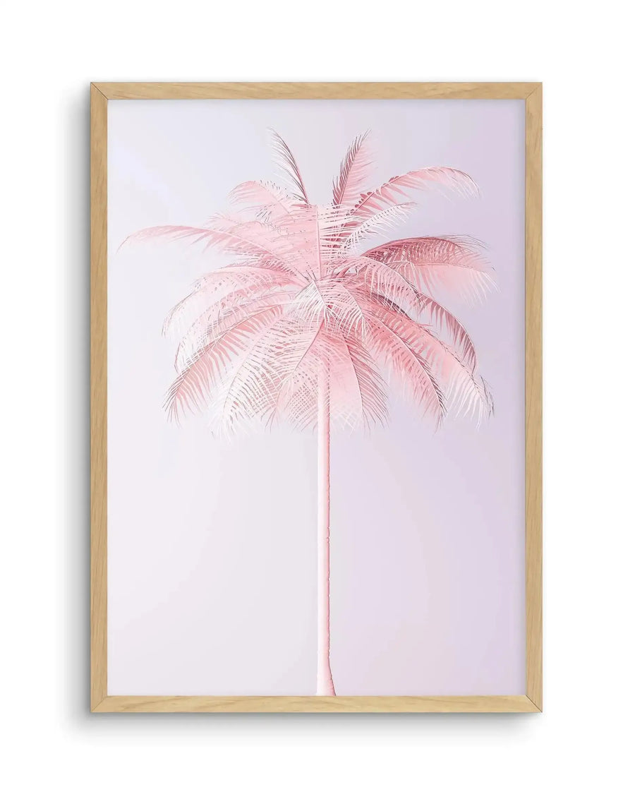 Framed art print featuring a single palm tree rendered in soft pink and mauve tones against a pale lavender background. The palm trunk is slender and delicate, extending vertically through the composition, while the fronds spread outward from the top in a full, feathered canopy with detailed line work showing individual leaflets. The illustration style is minimalist and botanical with a watercolor-like quality. The artwork is mounted in a natural wood frame with a white border.