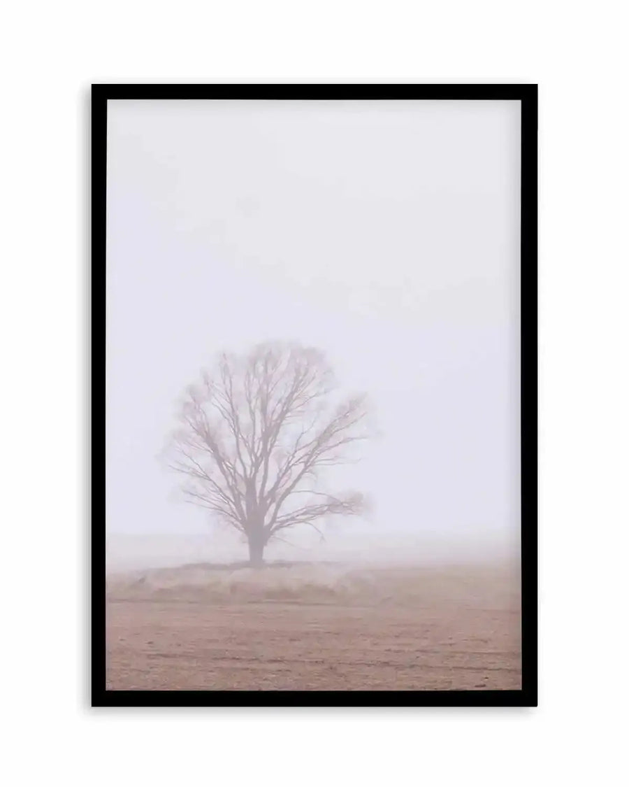 Framed photography art print featuring a solitary, bare tree in a vast, misty field, with a black frame and white border. The composition captures a serene, ethereal mood with soft, muted tones of pale lavender-grey in the sky and a warm, dusty brown in the foreground.