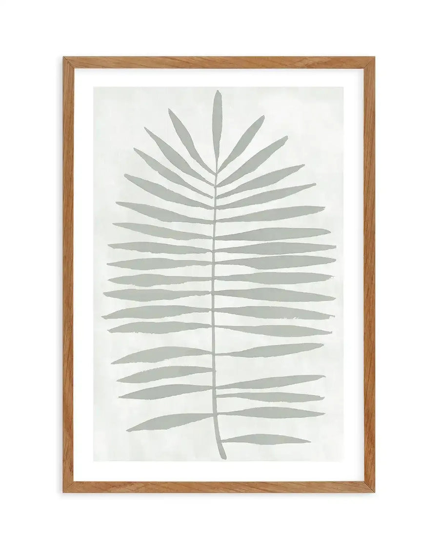 Watercolour art print featuring a large-scale sage green palm leaf with visible brushstroke texture on a soft white background, printed on fine art paper and displayed in a natural oak frame with white border.