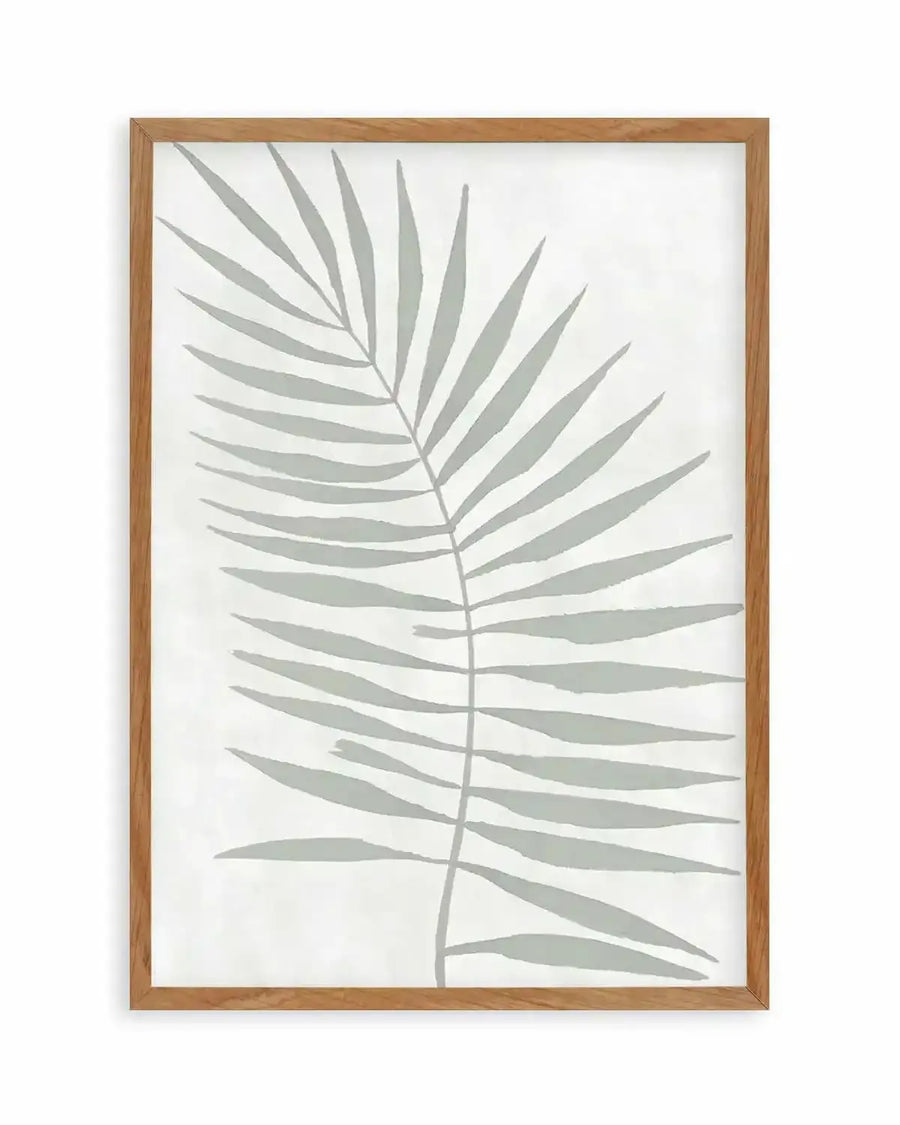 Art print featuring a single palm frond illustration in a muted sage green on a soft white background, printed on fine art paper and displayed in a natural oak frame with white border