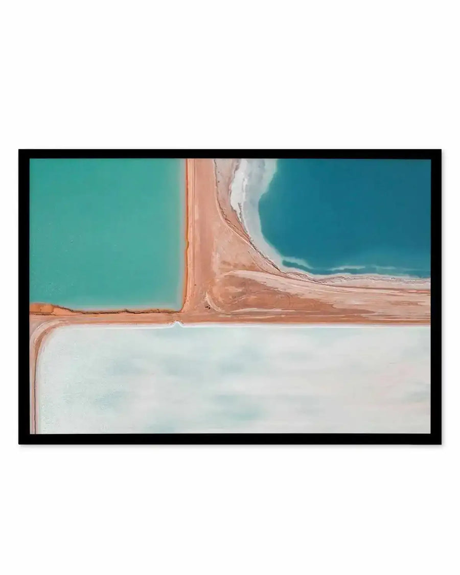 Framed aerial photography print of salt fields with distinct sections of water in varying shades of teal, deep blue, and pale turquoise, separated by narrow strips of reddish-brown earth. The composition creates a geometric abstract pattern, displayed in a black frame with a white border.