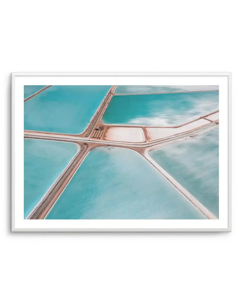 Framed aerial photography art print of salt fields with a white frame and white border. The composition features various rectangular and irregular-shaped pools of water in shades of turquoise, pale blue, and light green, separated by narrow, light brown landforms. Some pools show cloud reflections on their surface, while others have a more uniform color.