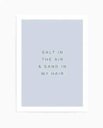 Art print featuring the phrase "SALT IN THE AIR & SAND IN MY HAIR" in simple black sans-serif font, centered on a pale blue background, displayed in a white frame with a white border.