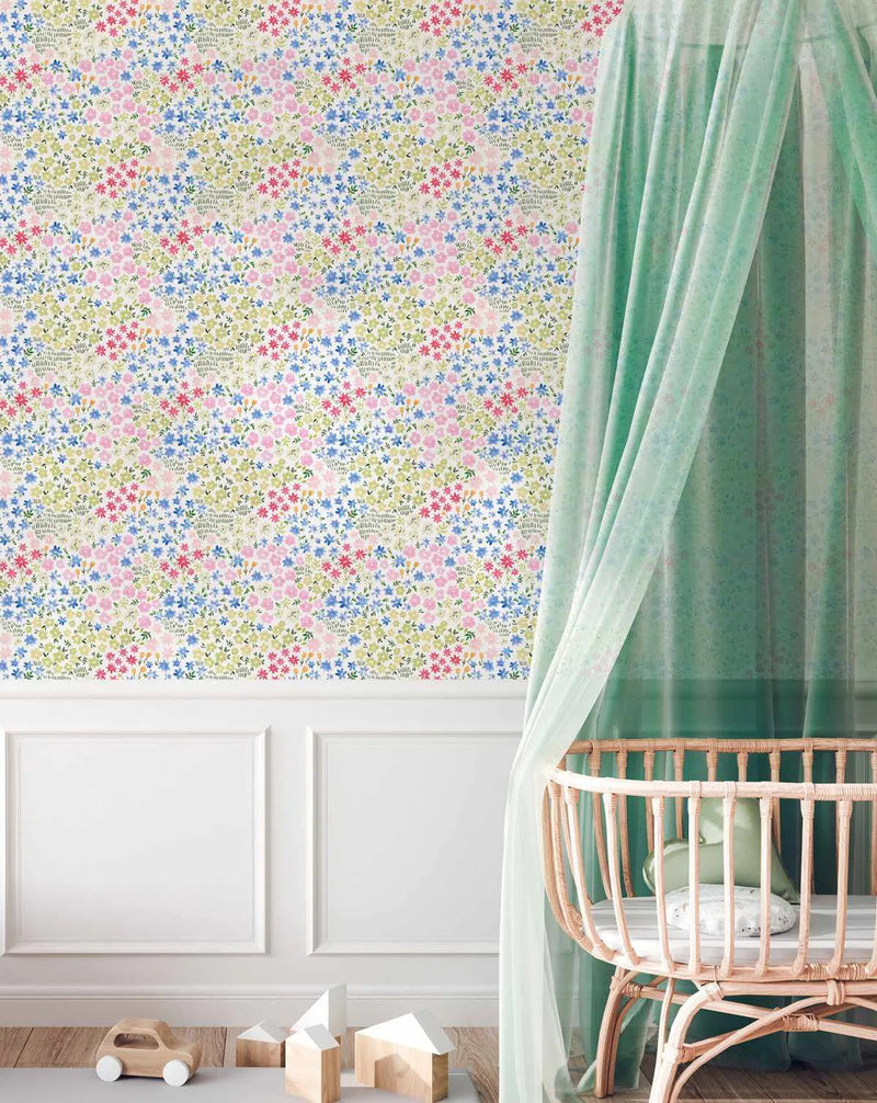 Nursery:
"Peel and stick wallpaper featuring a repeating pattern of small, delicate wildflowers in horizontal stripes of soft pink, light blue, and sage green on a cream background, displayed in a bright nursery. The wallpaper covers the upper half of the wall above white wainscoting. A light wood crib with a sheer mint green canopy stands on the right, and wooden toy blocks and a car are on the floor."