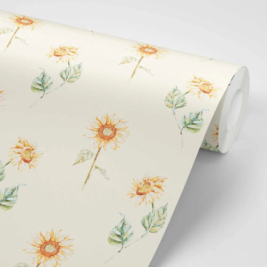Peel and stick wallpaper featuring a repeating pattern of hand-painted sunflowers in varying stages of bloom, with bright yellow petals and orange-brown centers, accompanied by sage green leaves on a warm cream background. The design has a loose, organic watercolor quality with visible brushstroke texture.