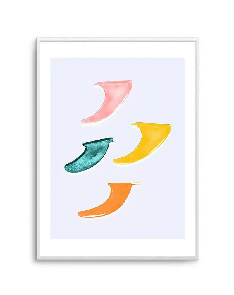 Watercolour art print featuring four surfboard fins in different colours and orientations on a light blue background, displayed in a white frame with white border. The top fin is pink, the middle left is teal, the middle right is yellow, and the bottom is orange.