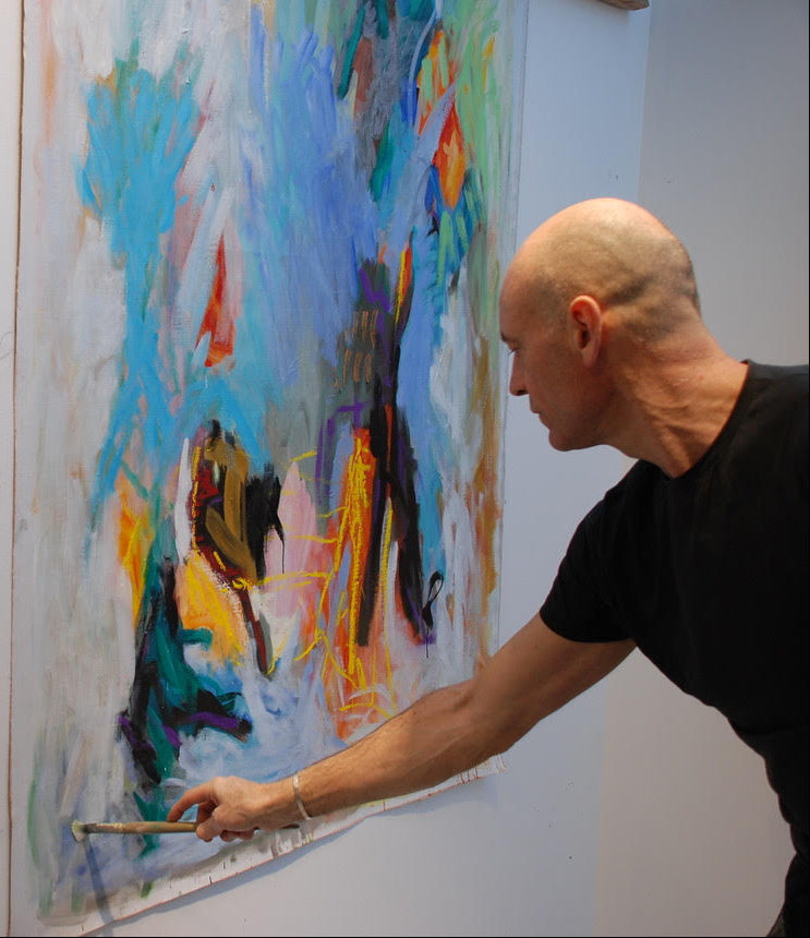 Man painting a colorful abstract artwork on a wall.