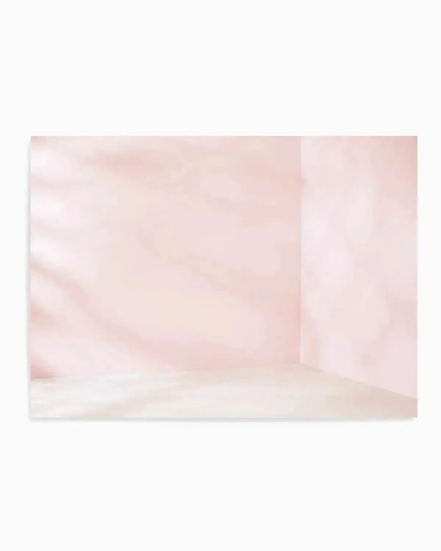A soft, minimalist art print depicting an empty interior room with pale dusty rose and cream-toned walls, subtle watercolor-style layering creating depth and shadow, natural light filtering across the left side, light wooden or beige flooring, and clean corner lines suggesting architectural simplicity, framed in white with a crisp white border.