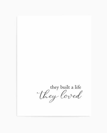 Art print featuring the phrase "they built a life they loved" in black script font on a clean white background. The first line "they built a life" is in a simple, elegant serif font, while the second line "they loved" is in a flowing, handwritten-style script.