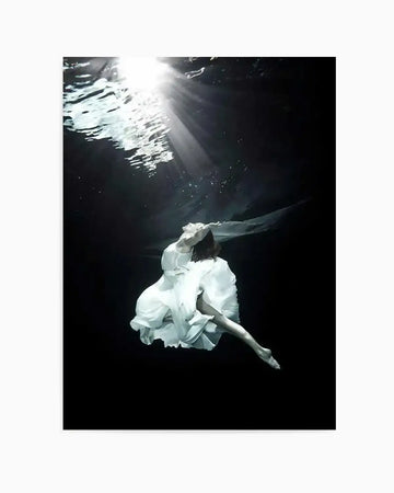 "Underwater photography art print featuring a woman in a flowing white dress suspended in dark water, with bright sun rays breaking through the surface from the top left. The woman's body is angled with her head tilted back, and her right leg is bent. The dark water creates a dramatic contrast with the bright light and the white dress, evoking a serene and ethereal mood."