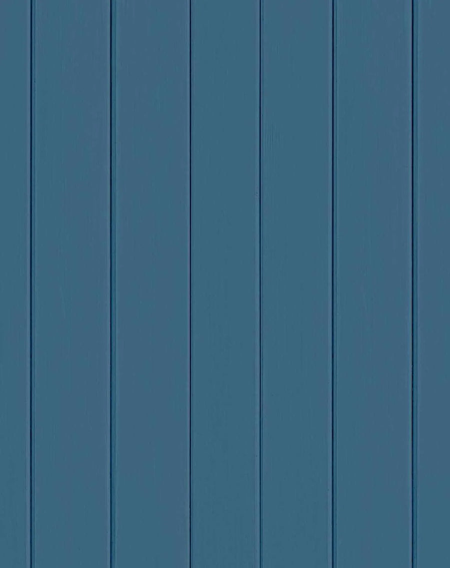 Peel and stick wallpaper featuring a repeating pattern of vertical tongue and groove wood panels in a solid, deep navy blue colour with a matte finish. The design shows subtle variations in tone and texture, mimicking painted wood.